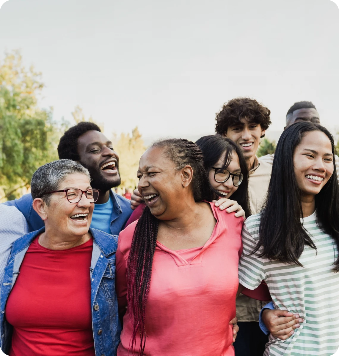 A diverse group of friends laughing and enjoying each other's company outdoors.