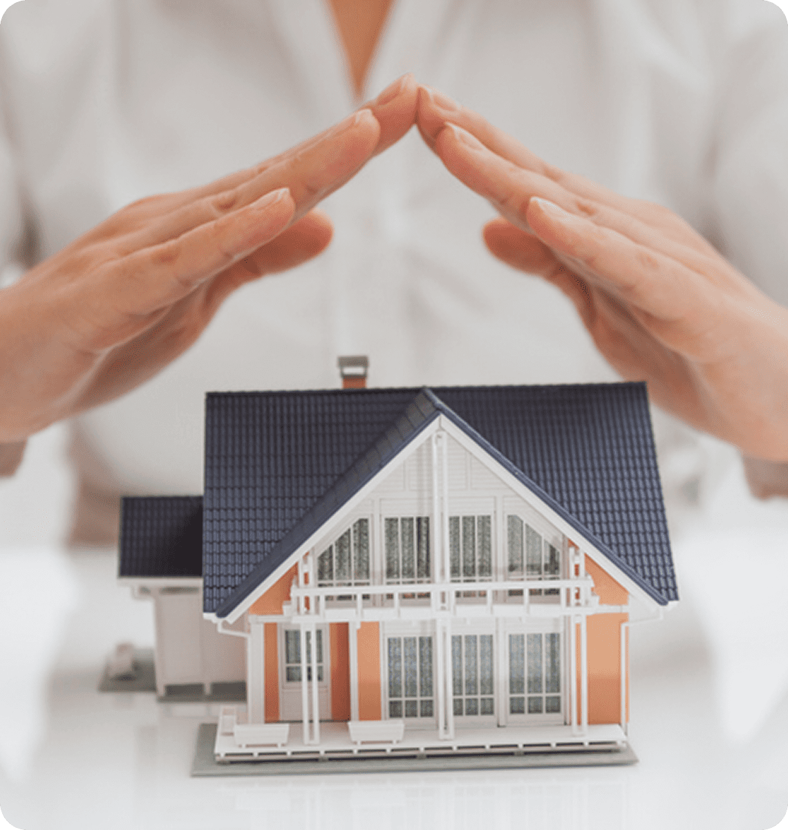 Hands protect a model house, symbolizing home security.