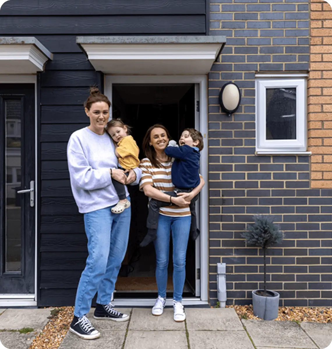 Happy family of four standing outside their new home.